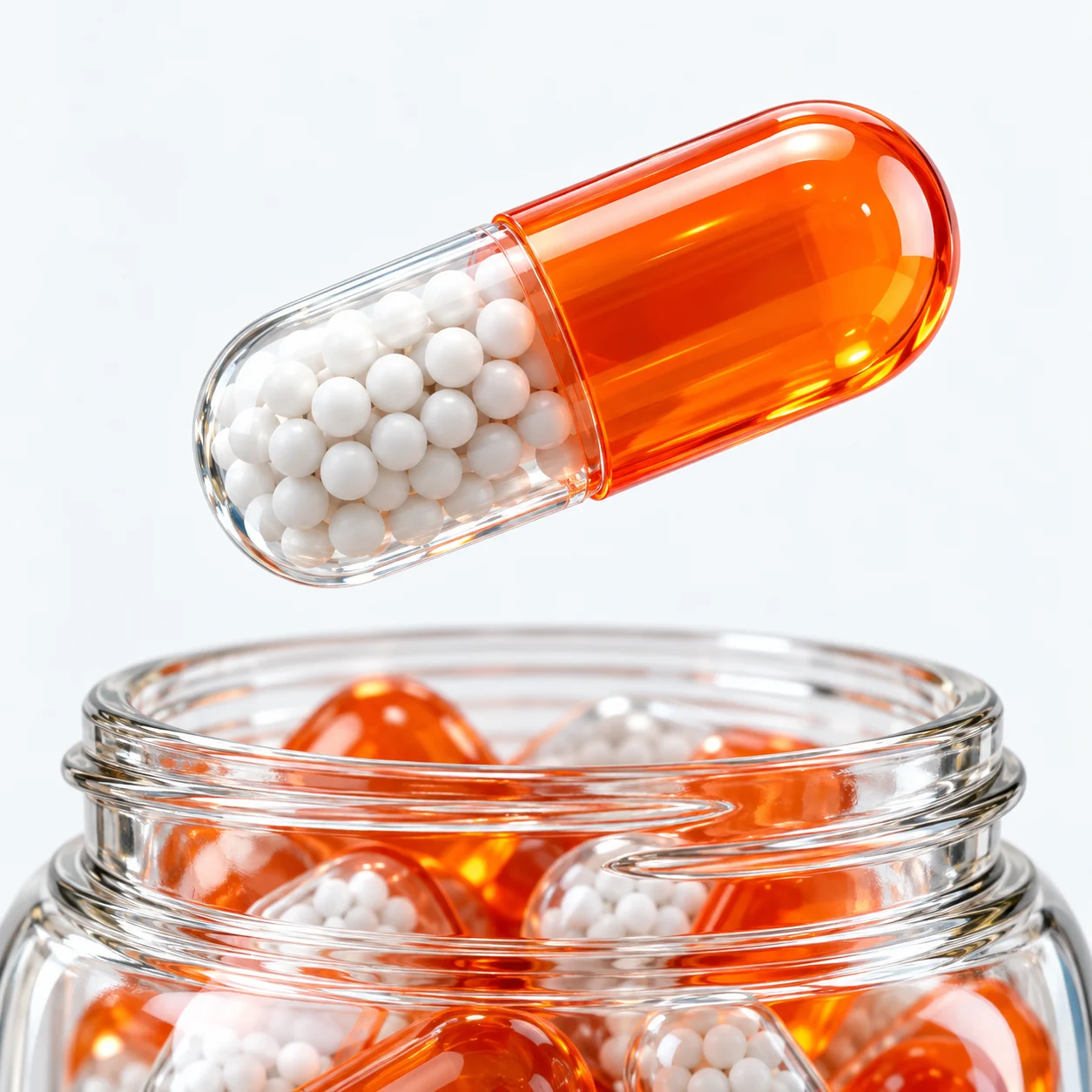 An orange capsule filled with tiny white spheres, floating above an open glass jar.